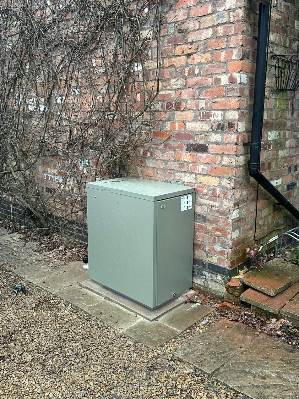 External oil boiler unit installed on a stone plinth against a brick wall